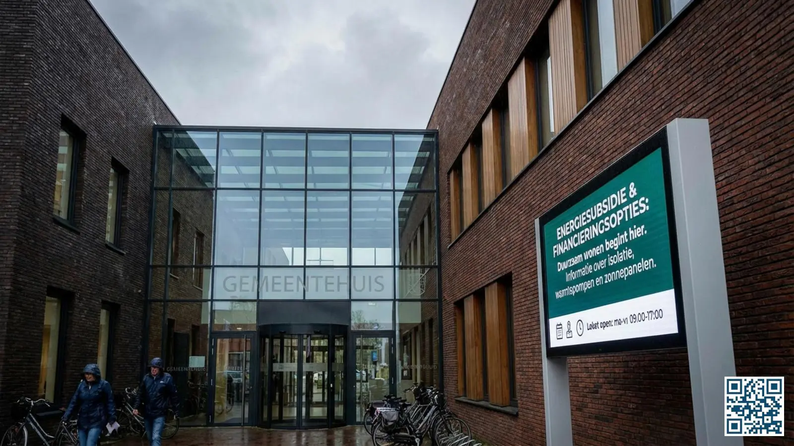 Ingang van een gemeentehuis met informatiebord over energiesubsidies en financieringsopties